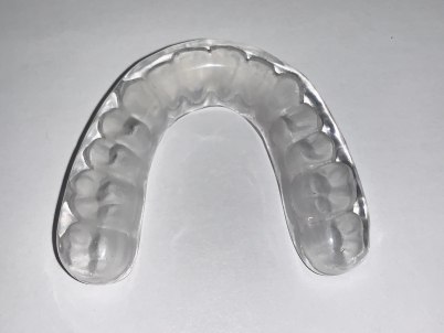 A clear plastic tooth against a white backdrop, representing the Impak nightguard in Atlanta, GA